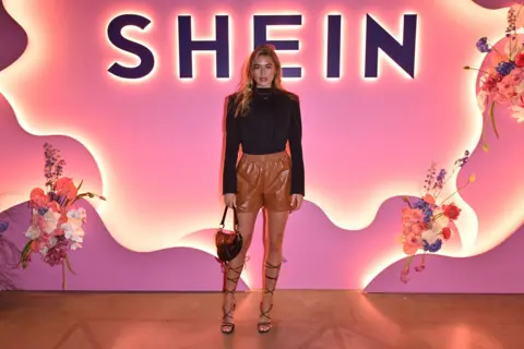 Getty Images Influencer and model Arabella Chi poses at a Shein event in front of a pink backdrop with flowers