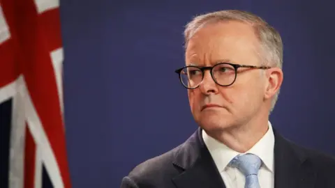 Getty Images Anthony Albanese in front of a blue background and the Australian flag