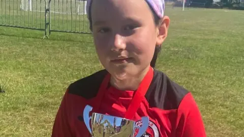 Holly, eight, with a football trophy