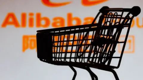 Getty Images A shopping cart is seen in front of the Alibaba Group logo.