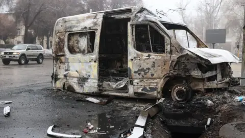 Getty Images A burnt minibus pictured in a street in Kazakhstan's main city, Almaty