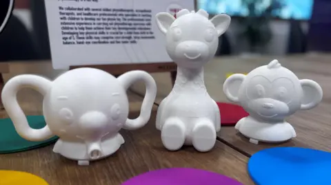 Three white plastic toys in the shape of an elephant, giraffe and monkey  