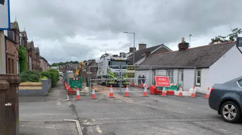 Getty Images A sign saying "road closed" with cones and railings put up on a road with houses down both sides
