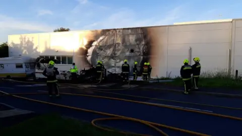 Avon and Somerset Police A group of firefighters stand next to a white building with a large silver and black burn mark