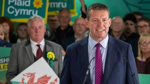 Getty Images Rhun ap Iorwerth speaking after the results at the count in Llandudno, surrounded by party supporters