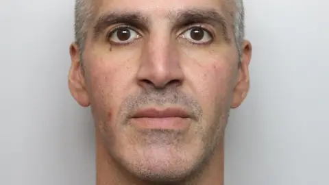 Thames Valley Police A police custody photo of Andrew Georgiou, with short grey hair and stubble.
