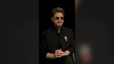 Shah Rukh Khan wearing black and black glasses.