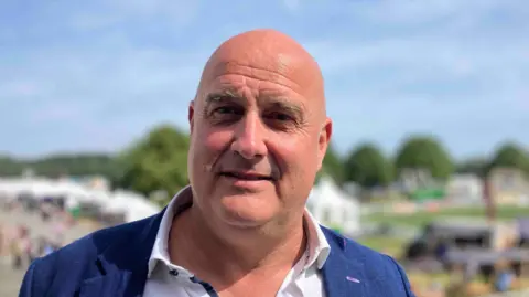 Richard Clothier looks at the camera with the Bath and West show behind him.