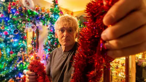 A man holds Christmas decorations. 