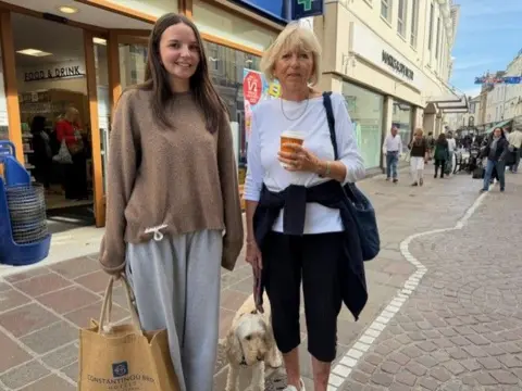 Izzie Vowden is pictured on the left with a brown jumper and grey tracksuit. Her grandma Eileen is on the right with a white top and black trousers.