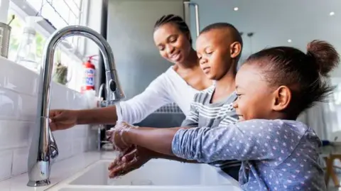 Stock photo of family washing hands in the kitchen sink