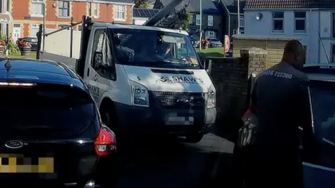 A van and a man looking in the window of a car