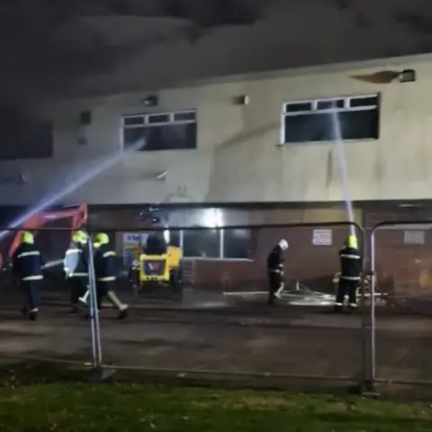 Jody Legg Firefighters can be seen spraying water into the windows of the a two-storey white building - the Low Grange social club. 