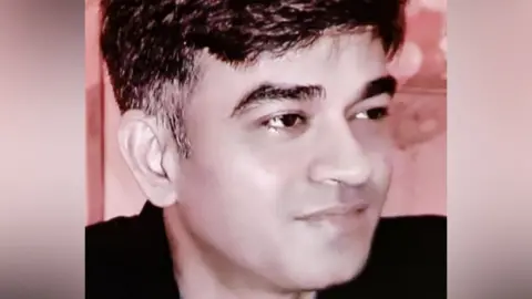 Chandranath Rath head and shoulders portrait seen in a black shirt looking away from camera.
