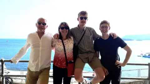 Paul, Jacqui and their two sons stood with the ocean in the background