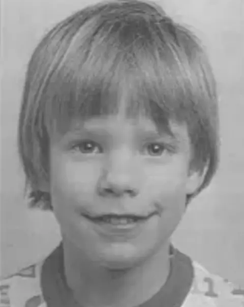 Getty Black and white photo of Etan Patz, smiling with short hair in a print T-shirt. He is shown from the shoulders up.