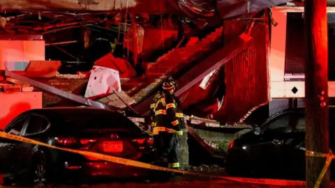 A fire worker stands by the mangled ruins of an exploded building