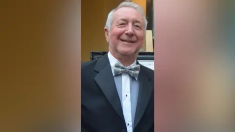 Thames Valley Police A man wearing a suit and a bow tie smiling into the camera. He is stood up.