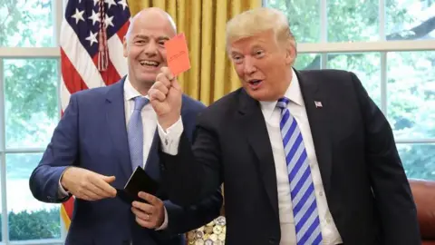 US President Donald Trump pretends to give a red card to members of the media while meeting with Fifa President Gianni Infantino at the White House in August 2018