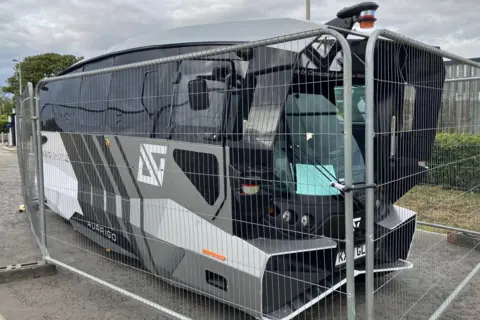 Car shuttle bus without driver on the Inverness Campus behind a fence