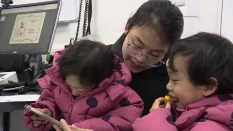 Thuy Mai  with her twin girls at a doctors surgery