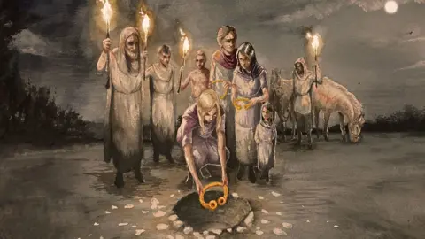 The Trustees of the British Museum An artist's impression by Craig Williams of a group of men and women and a child dressed in lose clothing, some holding torches, one man standing towards the back, holding a torch and in front of two horses. A woman is bending down in front of the group to place a gold Iron Age torc into a pit in the ground. It is night so the image is in grey tones, with the moon to the far right and shadowy trees glimpsed on the left.