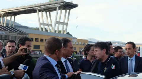 AFP Italian Prime Minister Giuseppe Conte (4th from R) visits the site after a section of the Morandi motorway bridge collapsed in Genoa on August 14, 2018