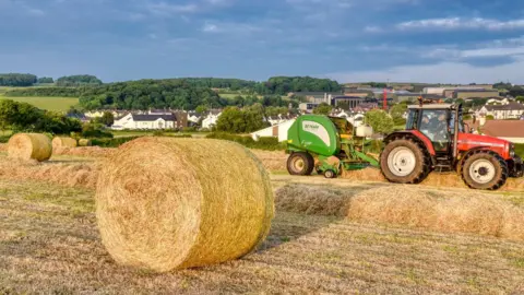 David North Farmers make round bales in a field in Ballymoney