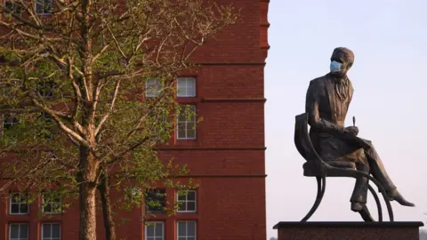 Getty Images A coronavirus mask on a statue in Cardiff Bay