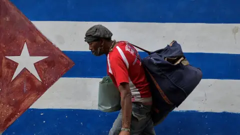 Getty Images A man walks next to a graffiti of the Cuban flag in Havana