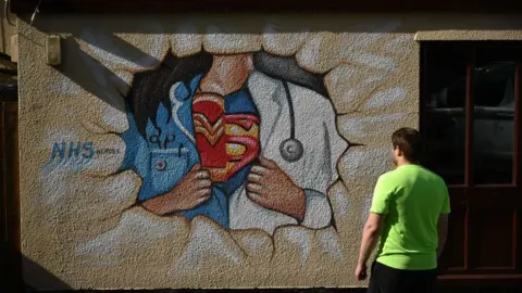 Getty Images A man looking at NHS superhero street art