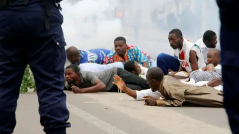 Reuters Protesters lie face down in front of security forces as clouds of tear gas swirl behind them. One man thrusts a hand forward, holding rosary beads aloft