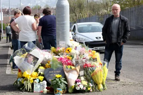 AFP A man looks at floral tributes to Lyra McKee close to where she was shot in Londonderry