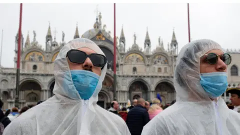 Reuters Tourists wear protective face masks at Venice Carnival