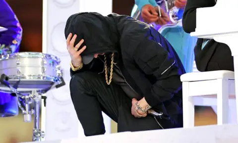 Getty Images Eminem takes a knee as he performs during the halftime show