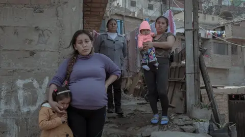 Florence Goupil Cinthia Estrada Bolivar (31) and her three-year-old daughter stand in front of their house accompanied by their relatives.