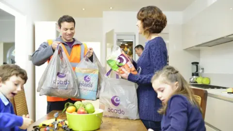 Ocado A food deliveryman puts bags of groceries on a table