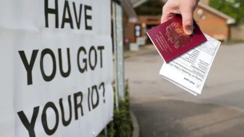 PA Media Voter carrying passport and poll card