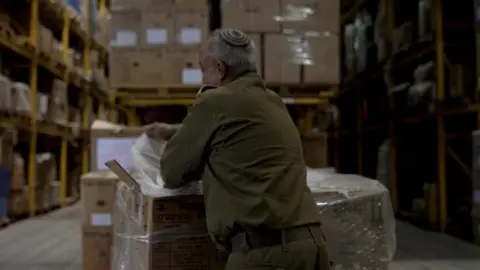 Reuters A man stands near aid and checks a list in Israel