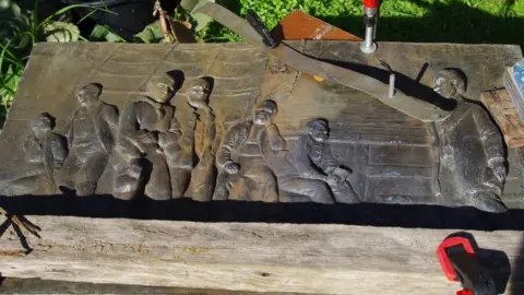 The damaged plaque being restored
