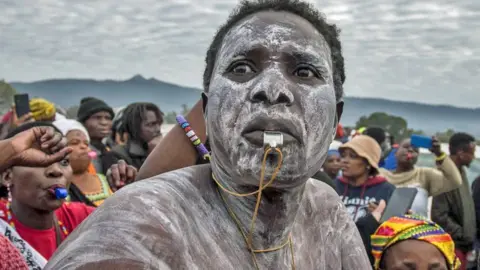 Man with a painted face blowing on a whistle
