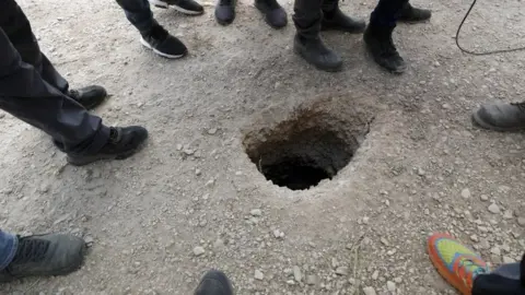 EPA Police officers and journalists gather around the exit of a tunnel allegedly used to escape from Gilboa Prison, northern Israel (6 September 2021)