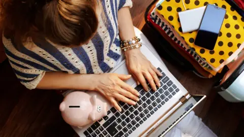 Getty Images Woman with computer and piggy bank