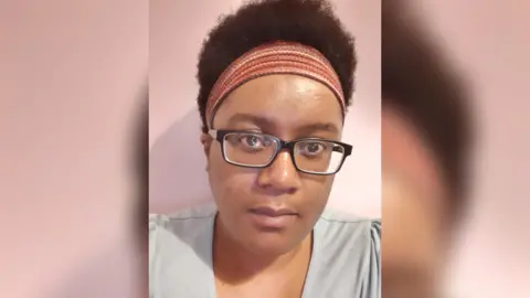 Cherokee Pilkington Image of Cherokee Pilkington, a woman with glasses and short dark hair in a red hairband