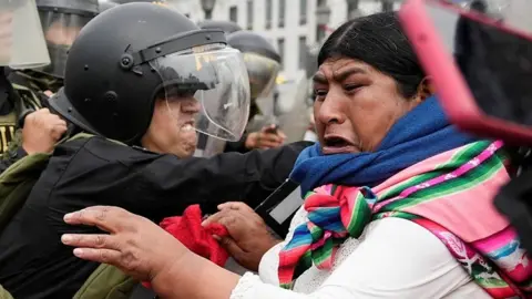 Indigenous woman clashing with line of police officers