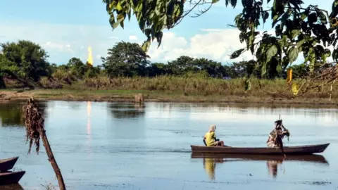 Getty Images Locals navigate a boat down a river in Assam