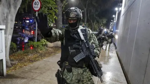 EPA A soldier gestures as military forces guard the headquarters of the Specialized Prosecutor's Office for Organized Crime (Femdo) following the transfer of Nestor Isidro Garcia 'El Nini', alleged head of security of Los Chapitos criminal group, in Mexico City, Mexico, 22 November 2023.