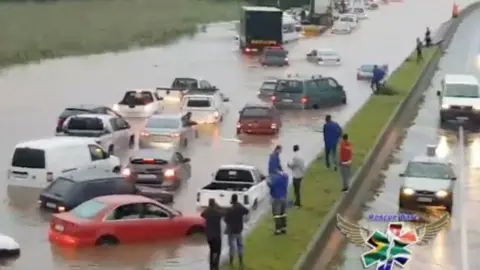 Rescue Care via Reuters People standing on a central reservation look at submerged vehicles on a flooded road during stormy weather in Durban, South Africa, 10 October 2017