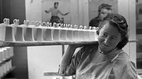 Janine Wiedel Pottery worker carrying ceramics