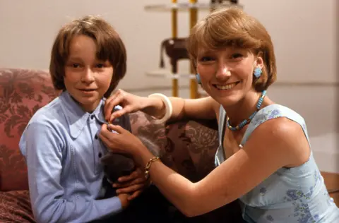 BBC Lesley Judd pinning a gold Blue Peter badge onto a child.